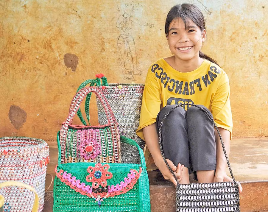 Em Rơ Mah San (làng Dơk Lah, xã Ia Dơk, huyện Đức Cơ) bên các sản phẩm thủ công được làm từ vật liệu tái chế. Ảnh: Minh Châu