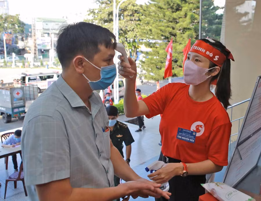 Các tình nguyện viên đo thân nhiệt cho người dân trước khi hiến máu. Ảnh Phan Lài