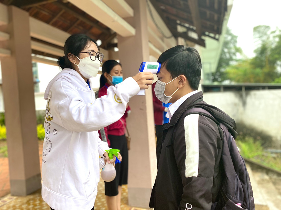 Vì trời mưa nên việc đo thân nhiệt và khử khuẩn cho thí sinh được điểm thi Trường THPT Pleiku thực hiện bên trong hành lang khuôn viên trường, công tác an toàn phòng dịch vẫn được đảm bảo trước khi thí sinh vào khu vực thi. Ảnh: Hồng Thi