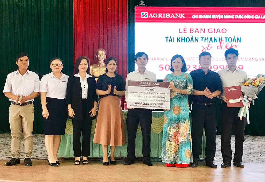  Chủ tịch Ủy ban MTTQ huyện Mang Yang Nguyễn Thị Thanh Nga (mặc bộ áo dài) tiếp nhận số tài khoản kèm kinh phí do Agribank Chi nhánh huyện Mang Yang ủng hộ phòng chống dịch Covid-19. Ảnh: Thanh Nhật