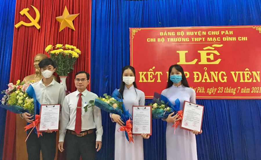 Thầy Lê Văn Tàu (thứ 2 từ trái qua)-Bí thư Chi bộ, Hiệu trưởng Trường THPT Mạc Đĩnh Chi (huyện Chư Păh) tặng hoa chúc mừng 3 đảng viên mới