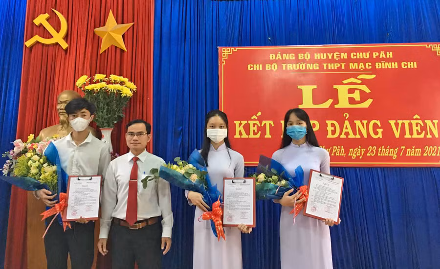 Thầy Lê Văn Tàu (thứ 2 từ trái qua)-Bí thư Chi bộ, Hiệu trưởng Trường THPT Mạc Đĩnh Chi (huyện Chư Păh) tặng hoa chúc mừng 3 đảng viên mới