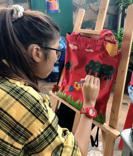 Một em nhỏ được trị liệu tại cơ sở của Công ty TNHH Hỗ trợ giáo dục trẻ khuyết tật Kim Yến Cao Nguyên (TP. Pleiku) say sưa vẽ trên túi xách. Ảnh: Phương Duyên