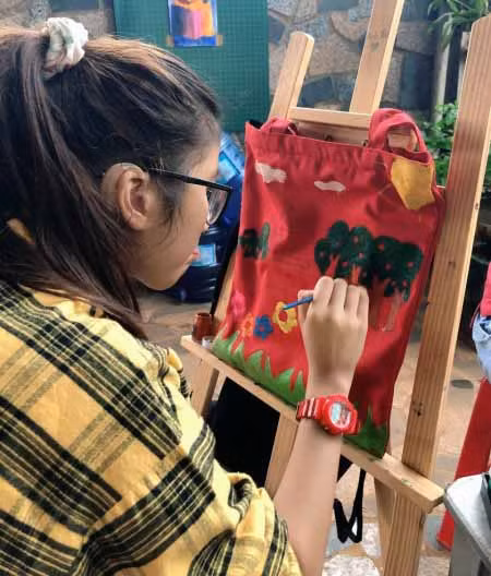 Một em nhỏ được trị liệu tại cơ sở của Công ty TNHH Hỗ trợ giáo dục trẻ khuyết tật Kim Yến Cao Nguyên (TP. Pleiku) say sưa vẽ trên túi xách. Ảnh: Phương Duyên