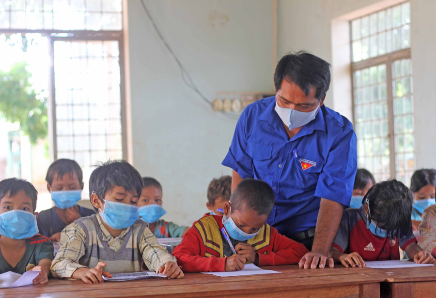 Anh Kpuih Muôn-Bí thư Đoàn xã Ia Kriêng (huyện Đức Cơ) hướng dẫn các em thiếu nhi làng Grôn học bài. Ảnh: Phan Lài