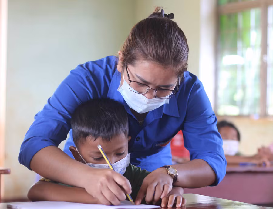 Ảnh 2: Chị Rơ Châm H’Hiền hướng dẫn các em nhỏ ở làng Ba (xã Ia Pnôn, huyện Đức Cơ) luyện chữ. Ảnh Phan Lài.