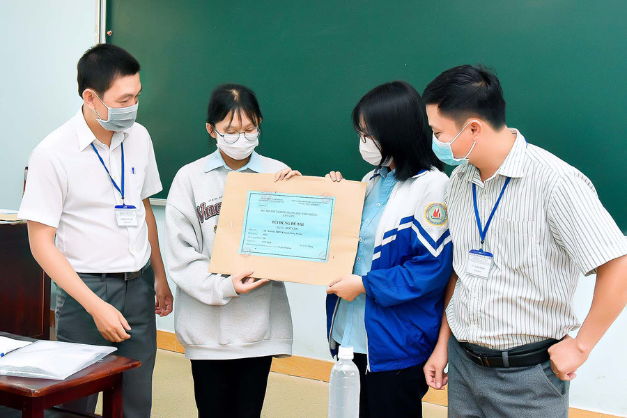 Thí sinh cùng giám thị kiểm tra dấu niêm phong của túi đề thi. Ảnh: Đức Thụy