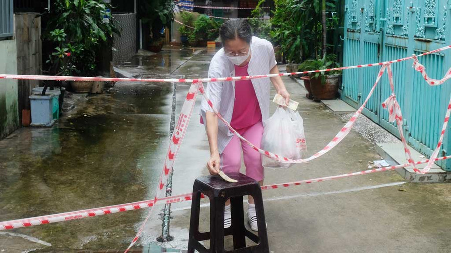 Người dân trong khu phong tỏa tại P.11, Q.11 ra nhận hàng giao đến. ẢNH: SONG MAI