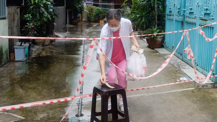 Người dân trong khu phong tỏa tại P.11, Q.11 ra nhận hàng giao đến. ẢNH: SONG MAI