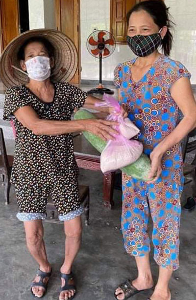 Một cụ bà góp ít gạo và quả bí xanh làm quà cho đồng bào TP HCM . Ảnh: VĨNH GIA