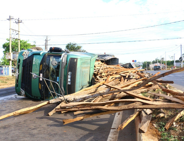 Chiếc xe tải chở gỗ lật nghiêng giữa đường.