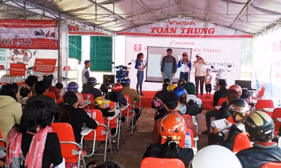 Nhân viên Công ty hướng dẫn người dân cách đội mũ bảo hiểm đúng.