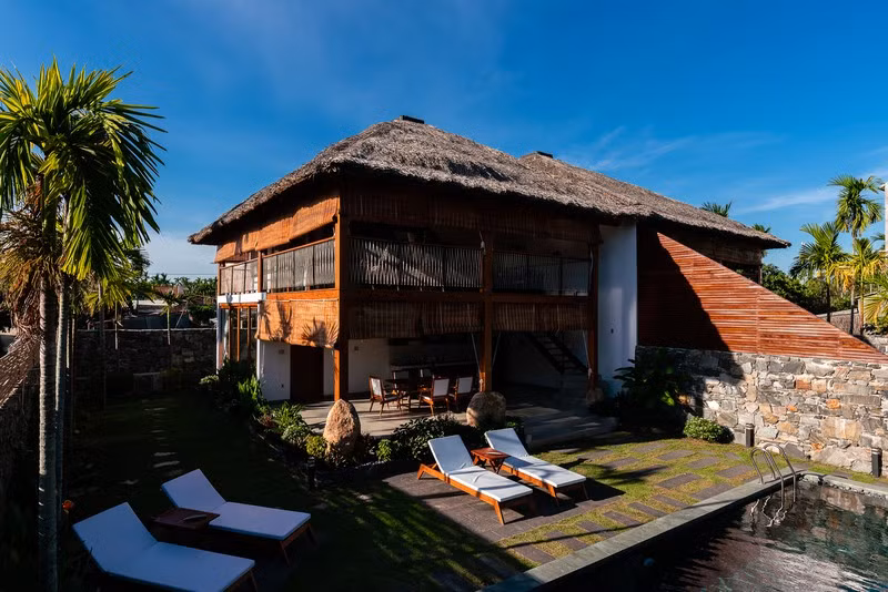  Mái nhà lợp bằng lá dừa nước, hạn chế xây tường rào xung quanh mà thay vào đó là những tấm rèm có thể đóng mở tự do.