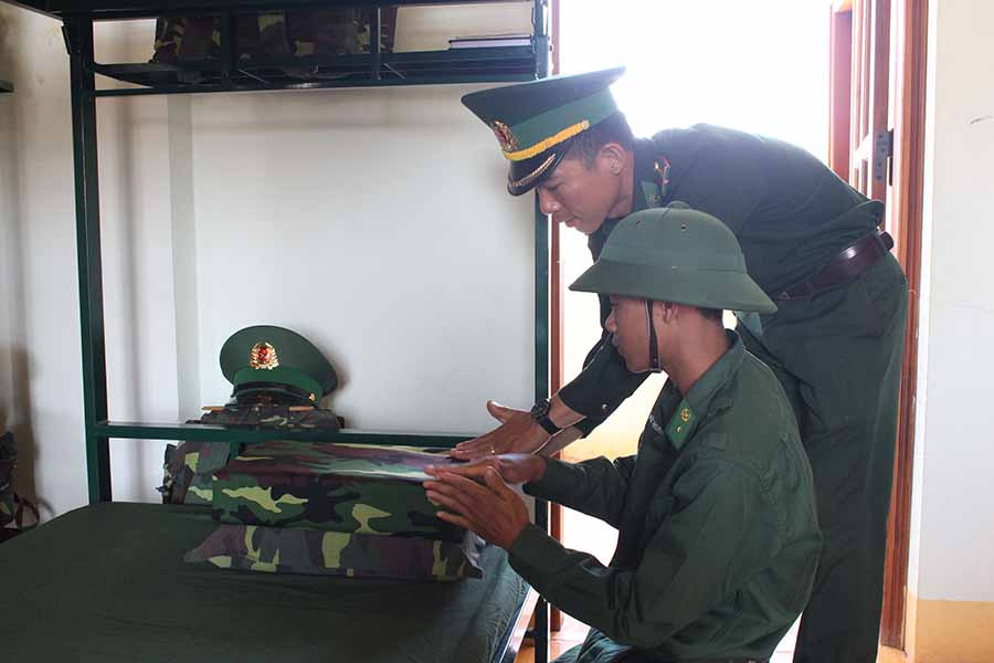  Cán bộ tiểu đội hướng dẫn chiến sĩ gấp xếp nội vụ. Ảnh: A.H