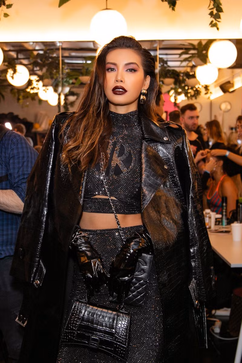 Cô chọn cho mình set đồ màu đen với áo crop top cao cổ, chân váy ôm dài cùng áo khoác da bên ngoài kết hợp với khuyên tai bản to, túi Chanel đeo chéo khiến tổng thể tuy đơn sắc nhưng lại rất nổi bật, cuốn hút và toát lên thần thái quyền lực của người đẹp. Được biết, từ make up đến kiểu tóc trong layout này đều được chính tay Minh Tú khéo léo thực hiện.