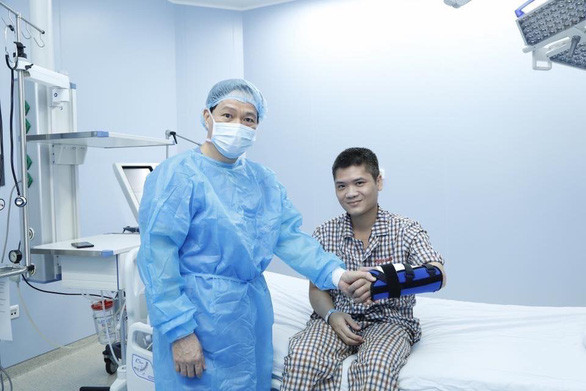 GS Hoàng và bệnh nhân Vương. Anh Vương cho biết anh rất cảm ơn người hiến tặng cánh tay. “Tôi sẽ tích cực tập phục hồi chức năng để có thể theo đuổi ước mơ của mình” - anh Vương nói - Ảnh: BVCC