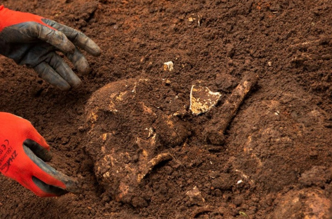 Nhân viên của Ủy ban Sự thật và Hòa giải phát hiện hài cốt trong cuộc khai quật các hố chôn tập thể ở tỉnh Karusi - Ảnh: Reuters