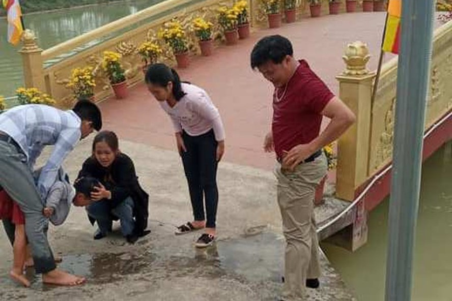 Cháu bé được thầy Mến (áo đỏ) dũng cảm lao mình xuống hồ cứu sống. Ảnh: ĐL
