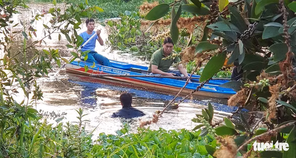 Lực lượng chức năng tìm kiếm vật chứng liên quan đến vụ án tại con kênh thuộc xã Phú Hòa Đông (huyện Củ Chi) vào chiều 7-2 - Ảnh: NGỌC KHẢI