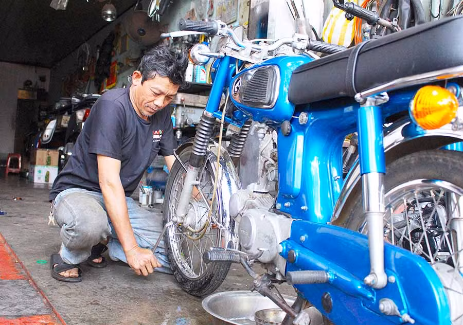  Ông Lê Nguyễn Bửu Khôi miệt mài sửa một chiếc xe Honda cổ cho khách. Ảnh: M.T