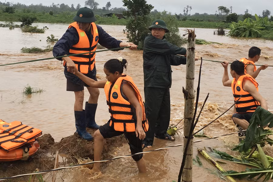 Cán bộ chiến sĩ dầm mình trong nước đưa dân lên bờ an toàn.