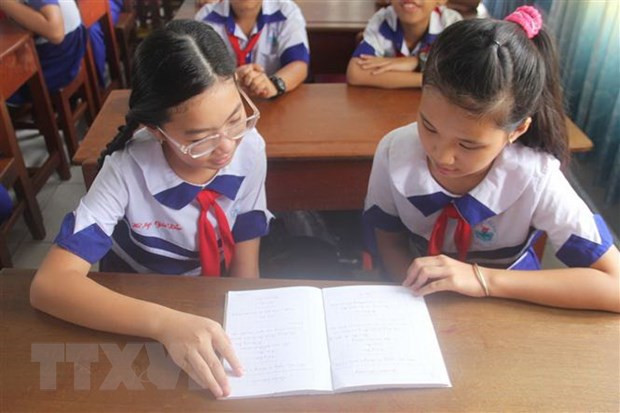 Em Võ Ngọc Gia Bảo (bên trái) trao đổi bài học với bạn cùng lớp. (Ảnh: Hữu Chí/TTXVN)