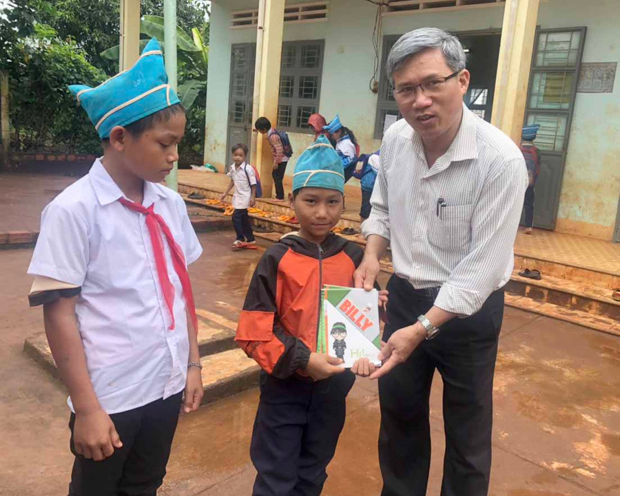 Ông Nguyễn Văn Bình-Bí thư Đảng ủy xã Ia Tôr (huyện Chư Prông) trao vở cho em Rơ Châm Thôi. Ảnh: Anh Huy