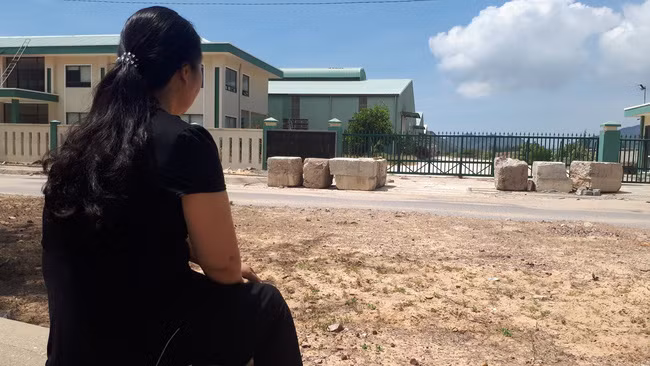 Bà Nguyễn Thị Quang thẫn thờ ngồi trước cảnh cổng đóng kín của Công ty Cổ phần dinh dưỡng Sinh học Rapid Việt Nam, sau khi tham gai vào công ty tới nay thiệt hại nhiều tỉ đồng (Ảnh: TX)