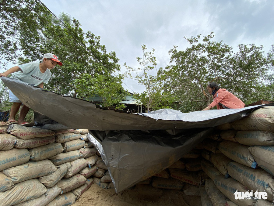  Người dân lợp bạt ni lông trên miệng hầm, sau đó chèn thêm một lớp tôn - Ảnh: LÊ TRUNG