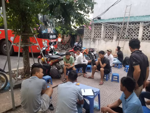 Nhóm “cò” bến xe chốt danh sách để đưa người lao động đến công trình - Ảnh: V.TUẤN