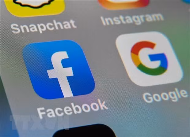 Biểu tượng của Facebook và Google trên màn hình máy tính bảng. (Nguồn: AFP/TTXVN)