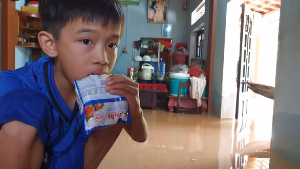 Sống trên đỉnh lũ, cháu Phùng Xuân Phúc, con anh Kỷ, đã 6 ngày phải ăn sáng bằng mì tôm sống - Ảnh: QUỐC NAM