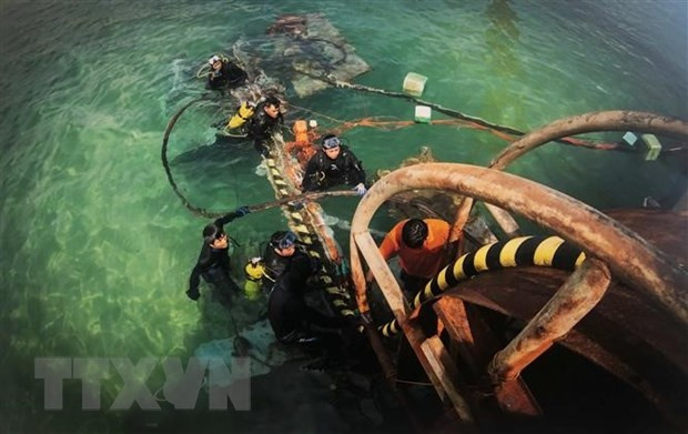 Công nhân Công ty trách nhiệm hữu hạn Xây dựng điện Thái Dương đang rải cáp ngầm xuống đáy biển. (Ảnh: Nguyên Linh/TTXVN)