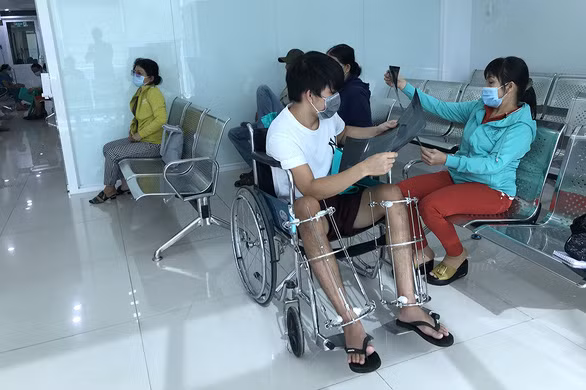 Tuấn và mẹ đi tái khám sau 3 tháng mổ kéo chân, hiện chân Tuấn đã kéo được khoảng 6cm - Ảnh: LÊ VÂN