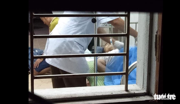 Nhân viên y tế cấp cứu cho thầy giáo bị thương nặng trong vụ tai nạn - Ảnh: QUÝ NGỌC