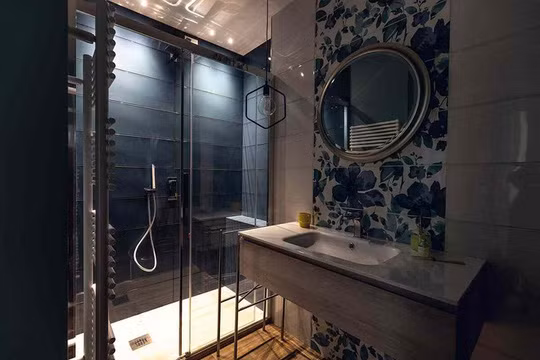 Phòng tắm hiện đại thêm sức hút với một viên gạch hoa màu xanh lam ngoại cỡ trên bức tường phía trên bồn rửa. Góc tắm vòi sen ốp gạch màu xanh thể hiện dụng ý sử dụng màu sắc trong thiết kế.