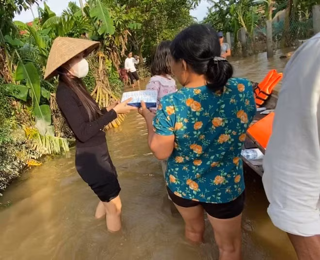 Nữ ca sĩ không ngại xắn quần, lội nước xuống trao quà tận tay mọi người.