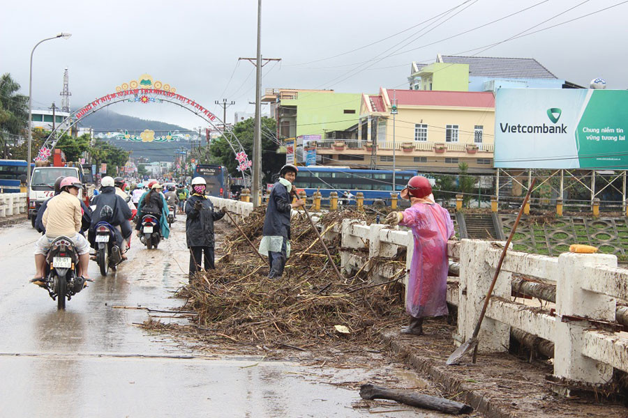 Rác thải do lũ kéo về kẹt trên thành câu sông Ba đang được dọn dẹp. Ảnh: Phương Linh