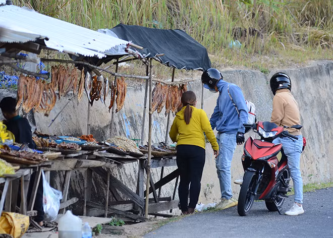 Thấy có xe máy hay ô tô chầm chậm qua, những phụ nữ bán hàng ra sát mép đường vẫy tay mời gọi.