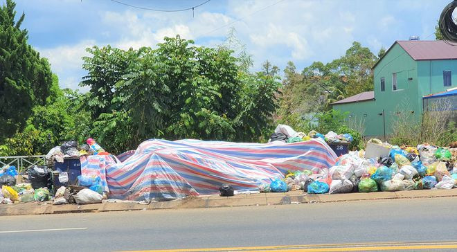Tại nhiều điểm chứa tạm quá tải buộc đơn vị thu gom rác phải che bạt hạn chế mùi hôi. ẢNH: TRÙNG DƯƠNG
