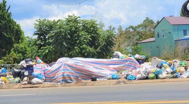 Tại nhiều điểm chứa tạm quá tải buộc đơn vị thu gom rác phải che bạt hạn chế mùi hôi. ẢNH: TRÙNG DƯƠNG