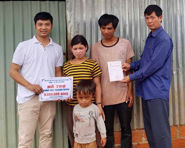 Ông Nguyễn Xuân Thủy-Chủ tịch Hội NNCĐDC/dioxin huyện Chư Sê (bìa phải) cùng đại diện Hội Bảo trợ trẻ em Việt Nam nhiễm dioxin (VNED) trao tiền hỗ trợ cho gia đình nạn nhân. Ảnh: Như Nguyện