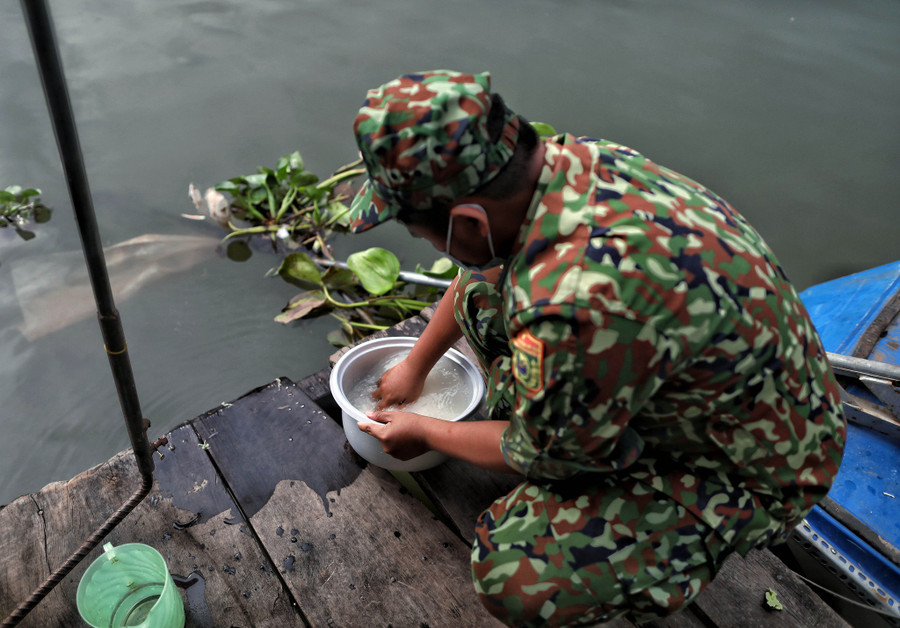 Trung úy Chao Sóc Chươn vo gạo để nấu bữa cơm chiều cho đồng đội ngay trên sông. ẢNH: NGỌC DƯƠNG