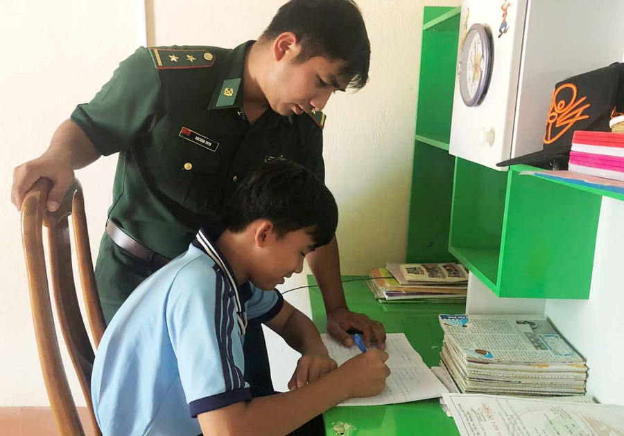 Trung úy Rơ Châm Tuyn hướng dẫn cháu Nguyễn Quốc Tĩnh học bài. Ảnh: Phương Dung Trung úy Rơ Châm Tuyn hướng dẫn em Nguyễn Quốc Tĩnh học bài. Ảnh: Phương Dung