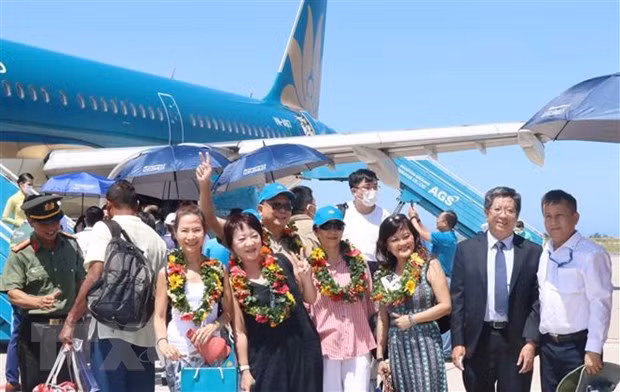 Các hành khách chụp ảnh lưu niệm khi vừa bước chân xuống sân bay Cam Ranh. Ảnh: Tiên Minh/TTXVN