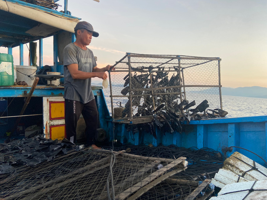 Ông Hảo chuẩn bị mồi và lồng bẫy mực. Ảnh: Thế Quang