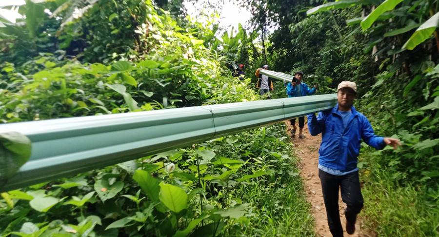 Đoàn viên, thanh niên vận chuyển tôn vào làng Pêtapot để xây nhà cho dân