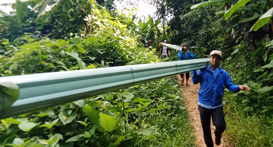 Đoàn viên, thanh niên vận chuyển tôn vào làng Pêtapot để xây nhà cho dân