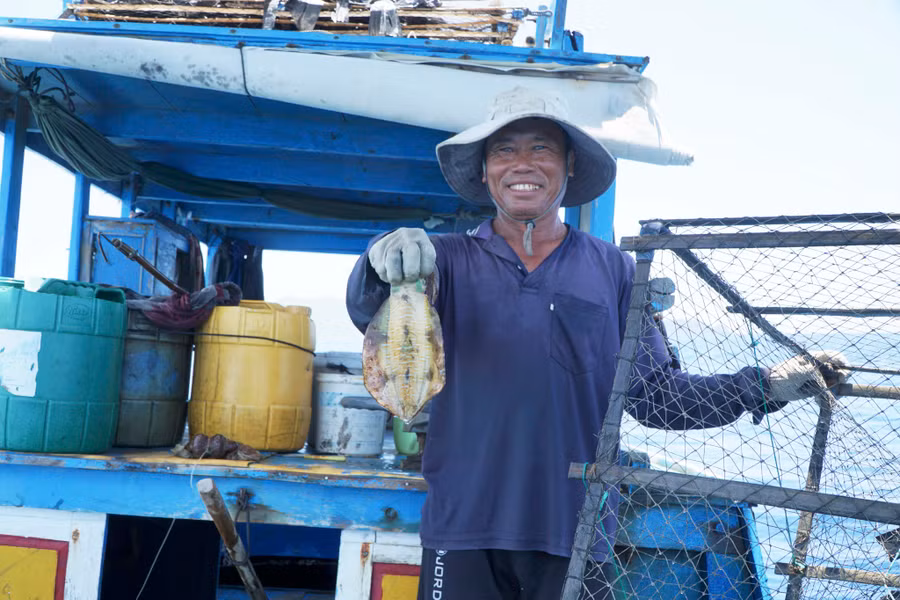 Ông Hảo phấn khởi khoe con mực vừa dính bẫy. Ảnh: Thế Quang