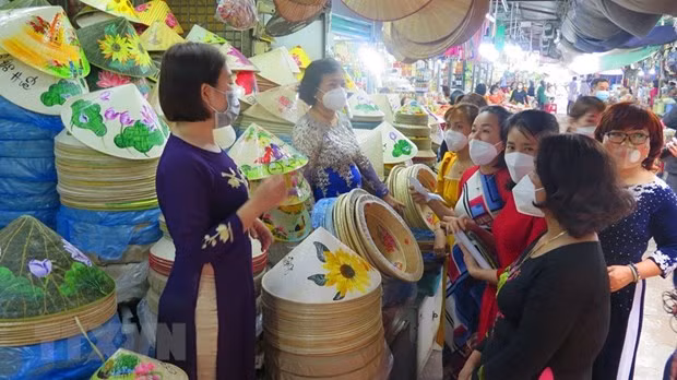 Tiểu thương chợ Đông Ba mặc áo dài nhưng vẫn thực hiện đeo khẩu trang. (Ảnh: Tường Vi/TTXVN)